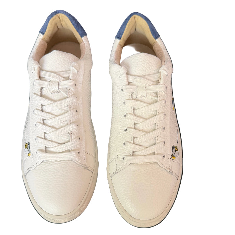 Pair of white sneakers with blue accents on a dark leather surface