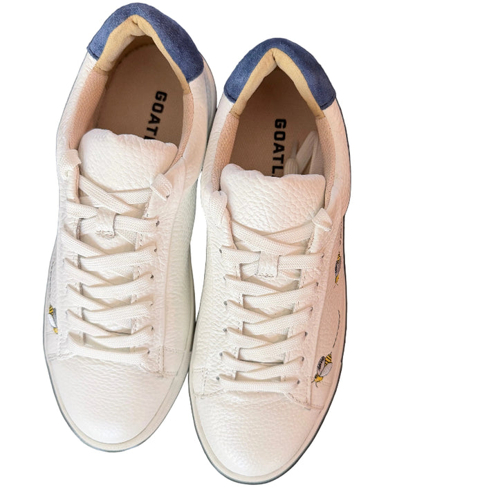 Pair of light pink sneakers with blue accents on a dark surface