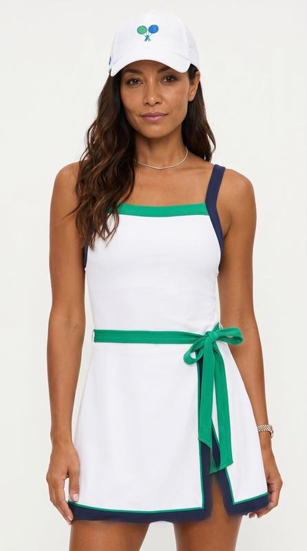 Woman wearing a white dress with green accents and a matching cap on a white background