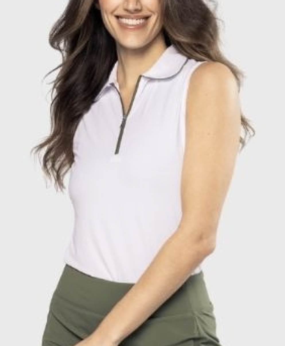 Woman wearing a sleeveless white blouse with a zipper and green pants on a light gray background