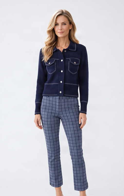 A woman modeling a navy blue cropped knit cardigan with button details and a matching navy blue and gray windowpane plaid cropped pant set, paired with white heeled sandals, against a light gray studio background.